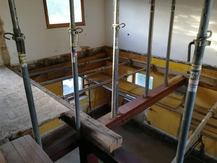 Stützpfeiler auf Querbalken stützen die Decke in einem Haus, in welchem der Boden zur Sanierung entfernt wurde